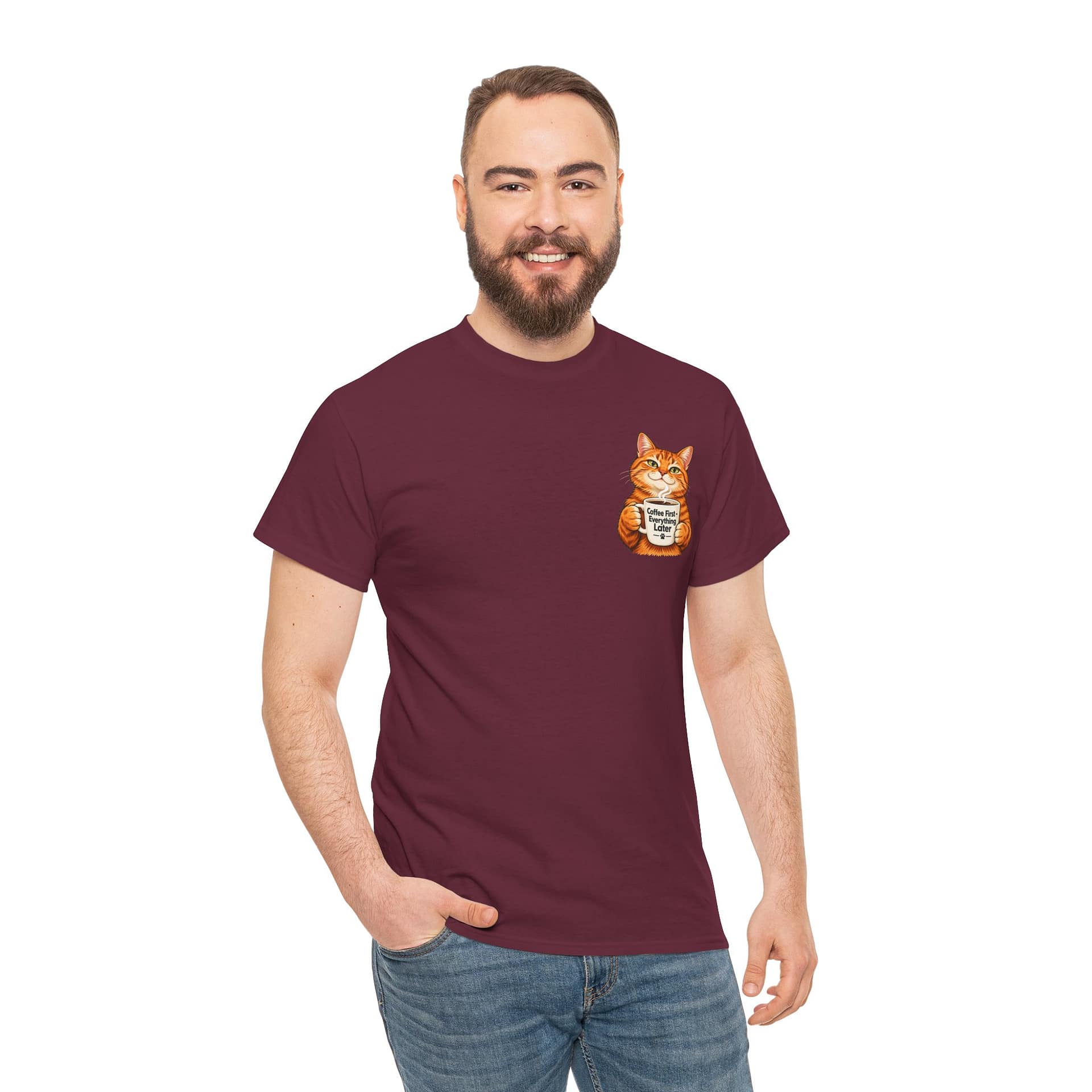 Cute orange cat holding a ‘But First Coffee’ mug printed on a unisex T‑shirt